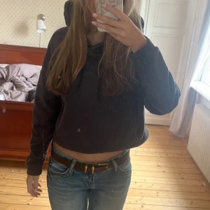 Svart/brun croppad hoodie med huva - Säljer en svart/brun croppad hoodie med huva och snörning framtill. Tröjan har lång ärm och är perfekt för dig som gillar en chill och avslappnad stil. Passformen är loose och materialet känns mjukt och bekvämt mot huden. #hoodie #comfortable #coolgirl #outfitinspo #y2k 