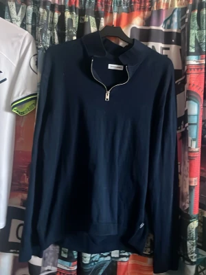 Mörkblå halvzip-tröja - Mörkblå långärmad tröja från Jack & Jones  med halvzip-dragkedja och ståkrage. Tröjan har en enkel, stilren design och är tillverkad i ett mjukt material. Tröjan är använd ett fåtal gånger