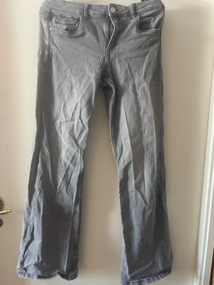 Gråa bootcut jeans med fickor - Säljer ett par gråa bootcut jeans med klassisk femficksdesign och snygga ficklock bak. Jeansen har vida ben och normal midja. Det går att stryka byxorna💞