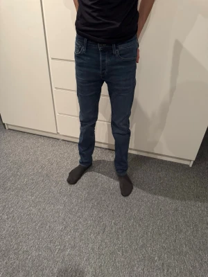 Mörkblå jeans från Jack & Jones - Säljer ett par mörkblå jeans från Jack & Jones med klassisk femficksdesign och raka ben. Jeansen har snygga kontrastsömmar och normal midja. Perfekta till en avslappnad stil och passar till det mesta. Materialet är mjukt denim som sitter skönt hela dagen.