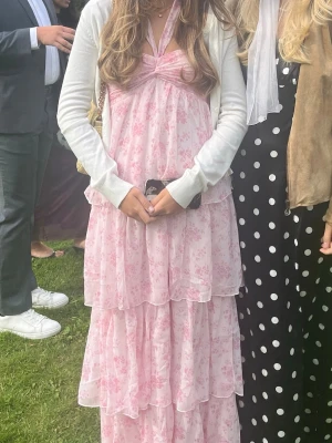 Rosa balklänning Nelly - Säljer denna otroligt fina långklänning perfekt till balen eller sommaren. Rosa med blommiga detaljer samt knytbar både runt halsen eller där fram. Endast använd en gång och därför i jätte fint skick! Hör gärna av dig vid frågor! Orginal pris 699kr