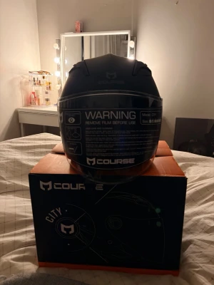 Svart MC-hjälm Course City - Snygg svart MC-hjälm från Course, modell City. Hjälmen har visir och modern design, perfekt för dig som vill ha både stil och säkerhet på vägen. Levereras i originalkartong.