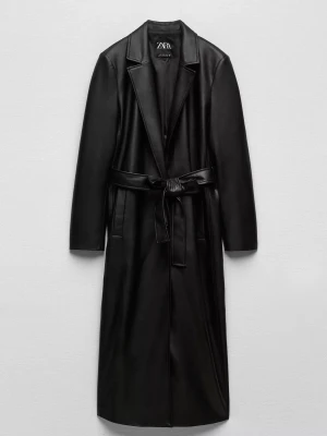 Svart lång kappa i skinnimitation Zara - Säljer en svart lång kappa från Zara i skinnimitation med klassisk krage och knytskärp i midjan. Kappan har raka ärmar och en stilren, minimalistisk design som ger en cool look. Perfekt för dig som gillar trendiga och snygga ytterplagg.