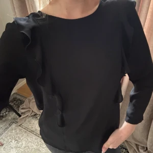 Svart blus med volangdetaljer - Säljer en gullig svart blus ifrån Gina tricot, använd 1 gång💕🌟inte min stil.