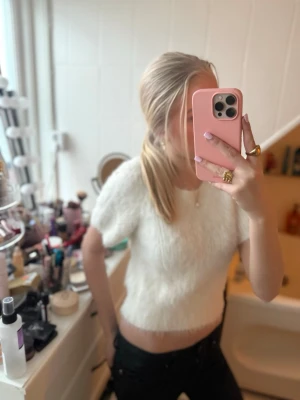 Vit stickad tröja ifrån Gina - Säljer en vit stickad cropped tröja från Gina Tricot. Tröjan har korta ärmar och är gjord i ett fluffigt, mjukt material som känns riktigt cozy. Perfekt att matcha med jeans eller kjol för en trendig look.