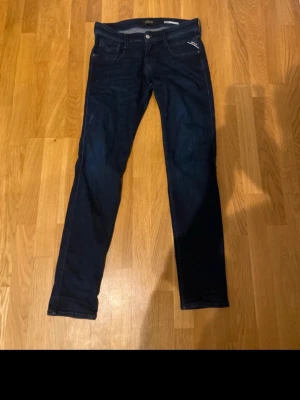 Mörkblå replay jeans - Snygga mörkblå slim fit jeans från Replay med klassisk femficksdesign och dragkedja. Jeansen har en smal passform och är tillverkade i stretchigt denimtyg för extra komfort. Perfekta för en trendig och avslappnad look.                  STRL: W30 L32