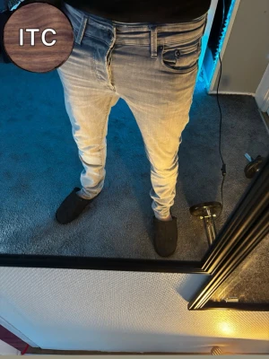 Ljusgrå Jack&Jones jeans - Säljer ett par ljusgråa slim fit jeans från jack&jones med klassisk femficksdesign och dragkedjegylf. Jeansen har en snygg tvättad look och smal passform som sitter tajt längs benen. Perfekta för en trendig och avslappnad stil.