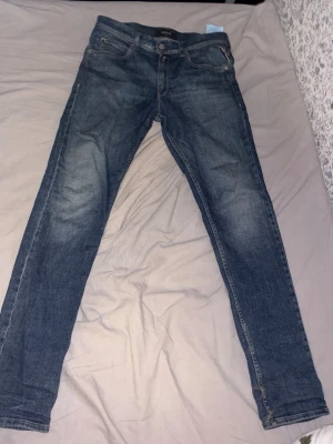 Replay Jeans - Snygga mörkblå slim fit jeans Replay med klassisk design. Jeansen har normal midja, raka ben och är tillverkade i mjuk denim med stretch för extra komfort. Perfekta för en avslappnad och trendig look. Köpta i butik och varsamt använda.