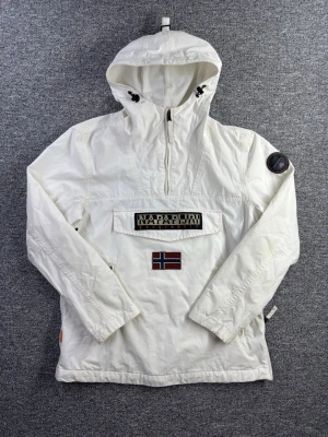 Napapijri Geographic Jacka – Storlek L - Napapijri Geographic anorak jacka i storlek L. Klassisk modell i vit färg med stor Napapijri logga framtill och flagga – riktigt clean outdoor / streetwear piece ❄️  📏 Storlek: L📐 Mått visas i bilderna✨ Skick: Bra skick – skicket visas tydligt i bilderna  Perfekt som vår/höst jacka eller för en clean streetwear look.  💸 Följ mig så får du 10% rabatt på köpet!  