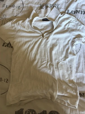 Vit kortärmad topp med dragkedja - Vit kortärmad topp från S.C.W. med krage och guldfärgad dragkedja framtill. Tillverkad i mjukt bomullsmaterial. 