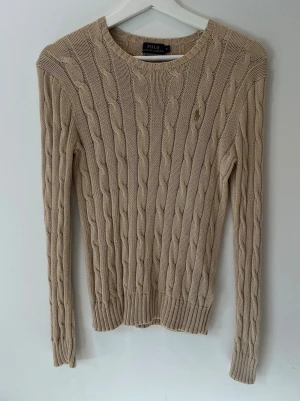 Beige tröja från Polo Ralph Lauren - Beige tröja från Polo Ralph Lauren med rund halsringning och diskret broderad logga på bröstet. Storlek S💗 Har ett hål på baksidan av kragen, se sista bild! Annars mycket bra skick!