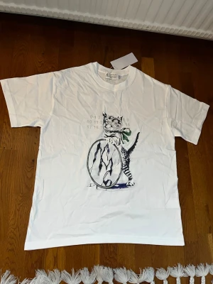 Maison Margiela Vit Katt, 2, S - Säljer denna t-shirt i storlek S, men skulle säga att den är stor i storleken och passar perfekt även för en M! 