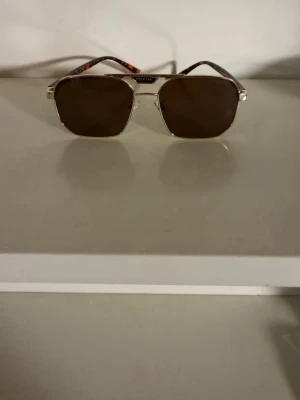 Prada solglasögon med guld och bruna bågar - Säljer mina Prada-solglasögon då jag köpt ett par nya och dessa bara blir liggande.  Sjukt snygga och passar till  allt. nytt skick! Hör av dig vid intresse eller om du vill ha fler bilder. 