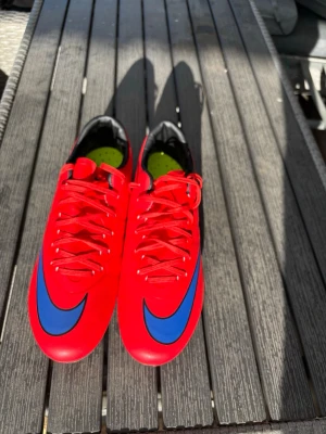 Nike Mercurial fotbollsskor – Röd – FG – Mycket fint skick - Säljer ett par Nike Mercurial fotbollsskor i en snygg röd färg. Skorna är i mycket fint skick och har endast använts ett fåtal gånger. Dobbarna är i bra skick och skorna är rengjorda. Lätta och bekväma med bra grepp, perfekta för spel på naturgräs. Säljs eftersom de inte längre används.