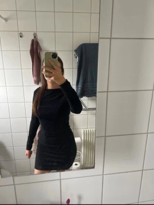 Svart glittrig kort klänning - Jag säljer en fin glitterklänning som passar perfekt till nyår, fest och andra tillfällen. Den har en liten öppning i ryggen och passar både för dom som har storlek XS eller S.