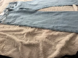 Ljusblå raka jeans med broderi(ordinarie pris:400kr) - Säljer ett par ljusblå jeans från LST med raka ben och snyggt broderade bakfickor i guldtråd. Jeansen har klassisk femficksmodell och är tillverkade i denim. Perfekta för dig som vill ha en unik touch på din outfit.
