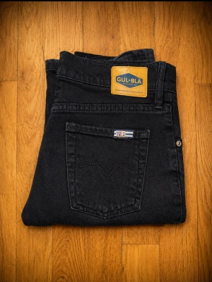 Gul & Blå svarta stretchjeans – stl 31 - Märke: Gul & Blå Storlek: 31 Färg: Svart Material: 98 % bomull, 2 % elastan Passform: Rak till lätt utsvängd modell Skick: Bra begagnat skick  Mått (platt mätta, utan att stretcha):  * Midja: ca 37 cm (ca 74 cm runt om) * Innerbenslängd: ca 85 cm * Ytterlängd fram: ca 108 cm * Ytterlängd bak: ca 110 cm