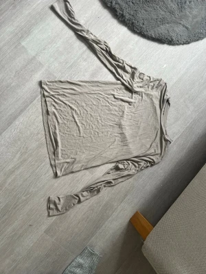Beige långärmad topp - En enkel och stilren beige långärmad topp i mjukt material. Perfekt att matcha med jeans eller kjol för en clean look. Toppen har en rak passform och rund halsringning.