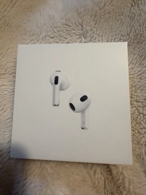 Apple AirPods med laddningsetui - Säljer vita Apple AirPods med Lightning-laddningsetui. Trådlösa in-ear-hörlurar med stilren och minimalistisk design. Perfekta för musik, samtal och vardagsbruk. Kommer i originalförpackning men ena AirPoden saknas (höger). 