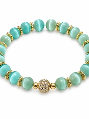 Armband med gröna cateyepärlor  - Armband med gröna cateyepärlor och guldfärgade detaljer. Armbandet har en glittrande guldfärgad pärla i mitten med små stenar, vilket ger en lyxig känsla. Perfekt accessoar för att lyfta din outfit med lite extra färg och bling. Ca 17 cm, elastiskt.