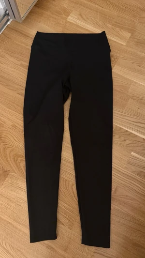 Svarta tights - Snygga svarta leggings med hög midja och tight passform. Perfekta för träning eller chill dagar. Tillverkade i stretchigt material som ger bra rörelsefrihet. Klassisk design utan synliga loggor eller detaljer. Ny utan prislapp