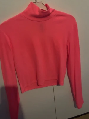 Rosa polotröja från Divided H&M - Säljer en rosa långärmad polotröja från Divided H&M. Tröjan är croppad och har en tight passform med mjukt stretchigt material. Perfekt att styla med höga jeans eller kjol för en trendig look.