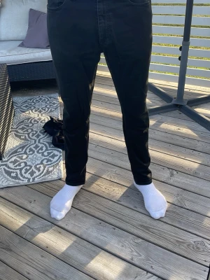 Svarta raka jeans - Säljer ett par svarta jeans med rak passform. Jeansen har normal midja och är tillverkade i ett mjukt denimtyg. Passar perfekt till en avslappnad stil och är lätta att matcha med olika plagg.