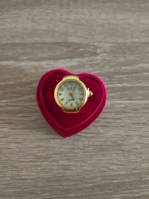 Guldig ringklocka från Quartz - Unik ringklocka från Quartz i guldtonad metall med vit urtavla och tydliga siffror. Klockan har ett elastiskt band som gör att den sitter bekvämt på fingret. Perfekt accessoar för dig som vill sticka ut med något annorlunda.