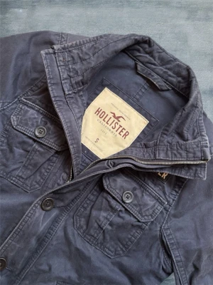 Marinblå Hollister Fieldjacket - En mycket trevlig fieldjacket från Hollister i storleken S! Hör av dig vid frågor! 