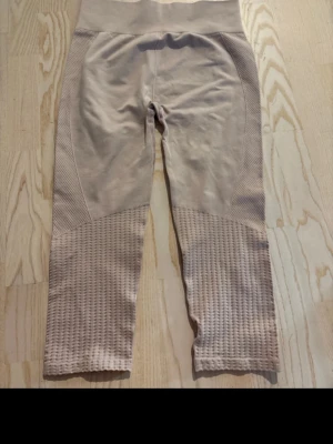 Beige seamless leggings med struktur - Säljer ett par beige seamless leggings med hög midja och snygga strukturerade detaljer på benen. Materialet är stretchigt och bekvämt, perfekt för träning eller chill. Inga synliga loggor eller märken. Croppad längd som slutar vid vaden. Vet tyvärr inte vart de är ifrån så lappen är bort klippt