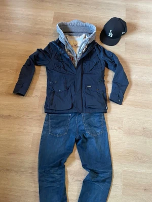 Mörkblå field jacket från superdry - Snygg mörkblå field jacket från superdry med flera fickor framtill, dragkedja och knappar. Jackan har hög krage och justerbara detaljer i midjan. Perfekt för en avslappnad, men endå stilig look.                                                                             Pris kan diskuteras vid snabb affär 