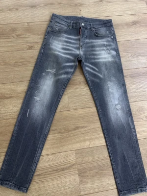 DSQUARED2 jeans - Snygga grå jeans från DSQUARED2 med slitningar och blekta detaljer framtill och baktill. Klassisk femficksmodell med raka ben och knappgylf. Märkespatch bak i midjan. Perfekta för en cool och avslappnad stil.