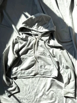 Ljusgrå cropped hoodie med dragkedja - Snygg ljusgrå cropped hoodie från Bik Bok med dragkedja framtill och huva. Hoodien har långa ärmar och en stor ficka på magen. 