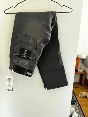 Grå raka jeans från Jack & Jones - Snygga grå jeans från Jack & Jones med rak passform och klassisk femficksdesign. Jeansen har en enkel look utan slitningar och är tillverkade i bomull med lite stretch för extra komfort. Perfekta till en avslappnad stil.