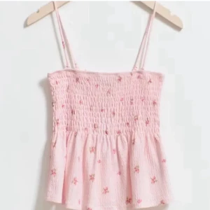Ljusrosa blommig linnetopp - Supersöt ljusrosa linnetopp med smock upptill och små blommiga detaljer. Hittar inte banden till