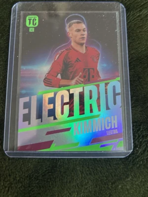 Panini Electric Kimmich samlarkort - Samlarkort från Panini med Joshua Kimmich i Bayern Münchens röda matchtröja. Kortet har holografiska detaljer och texten 'ELECTRIC' i stora bokstäver. Baksidan visar statistik och spelarinfo. Kortet ligger i ett plastfodral.