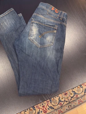 Dondup George Jeans - Säljer ett par blå dondups med slitningar och ljusa tvättade partier. Jeansen har fem fickor, smal passform och coola slitningsdetaljer framtill och baktill, alla från fabrik. Perfekta för en avslappnad streetstil. George w32