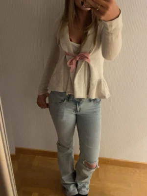 Beige kofta med rosa rosett Odd Molly - Supersöt beige kofta från Odd Molly med lång ärm och volangkant nertill. Koftan knyts framtill med en rosa rosett och har en feminin, avslappnad passform. Perfekt att slänga över en topp för en gullig look. Älskade denna tröjan men tyvärr har den blivit för liten så blir tvungen att sälja. Köpte för typ 400 så säljer för 320 men pris går att diskutera💕💕 skulle säga att den passar xs och s