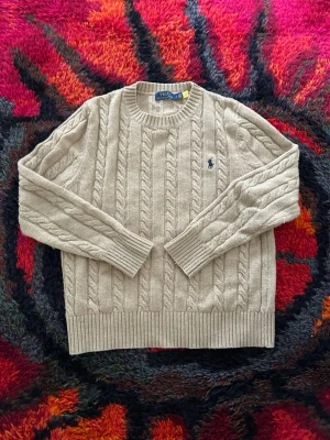 Kabelstickad Polo Ralph Lauren Tröja - Snygg beige kabelstickad Polo Ralph Lauren tröja i storlek S, mycket bra skick utan fläckar eller sönder på något sätt, säljer den då den inte passar mig längre, pris inte hugget i sten.