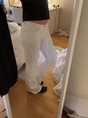 Vita bootcut jeans  - Säljer ett par vita bootcut jeans med klassisk femficksmodell från Lindex. Jeansen har en snygg, figurnära passform upptill och lätt utsvängda ben. Som ni ser har jag sytt ner dem och sytt ihop dem mellan benen men det är inget som synts speciellt mycket. Perfekta för dig som vill ha en clean och fräsch look. Materialet känns stretchigt och bekvämt.