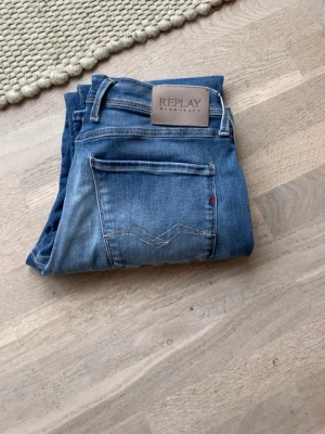 Replay anbass  - Snygga blå jeans från Replay Hyperflex med klassisk femficksmodell och raka ben. Jeansen har ljus tvätt med slitningar framtill och dekorativ söm på bakfickan. Skinnpatch med Replay-logga bak i midjan. Perfekta för en avslappnad och trendig look storlek 32/30 .