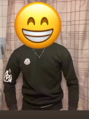 Svart sweatshirt från Moncler - Cool svart sweatshirt från Moncler med logotyp på bröstet och ett stort vitt tryck på ena ärmen. Tröjan har rund hals och är tillverkad i mjukt material som passar perfekt till streetwear-stilen.