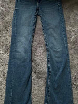 Blå bootcut jeans med fickdetalj låg midja - Säljer ett par klassiska blå bootcut jeans med snygga kontrastsömmar och liten ficka fram. Jeansen har normal midja och är tillverkade i denim med lätt tvättad look. Perfekta för en avslappnad och trendig stil. Storlek 164 men typ som xs/s