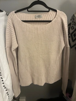 Hunkydory Essentials Tröja - Snygg beige stickad tröja från Hunkydory Essentials med rund halsringning och ribbstickad struktur. Tröjan har långa ärmar och en avslappnad passform, perfekt att matcha med jeans eller kjol. Materialet känns mjukt och bekvämt.