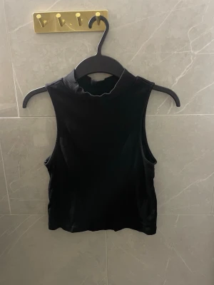 Svart ribbad ärmlös croppad topp - Snygg svart croppad topp med ribbad struktur och hög hals. 