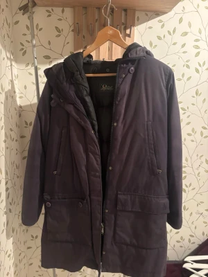  Park jacka från Peak Performance - Säljer en snygg lila parkas från Peak Performance med huva och dragkedja. Jackan har två stora fickor framtill och en innerjacka för extra värme. Perfekt för kalla dagar och har en stilren look med diskreta detaljer.