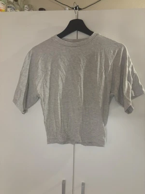 Grå T-shirt/ top  - En grå tröja som är lite tightare runt magen och lose uppåt. Väldigt skönt material och andvänt ett antal gånger men har fortfarande väldigt bra skick. Skrynklig då den inte kommit till användning💕