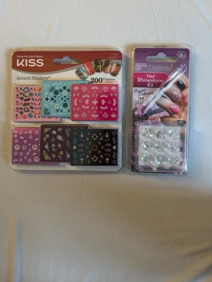 Nageldekorationer och rhinestones kit - Säljer ett set med nageldekorationer från KISS med över 200 stickers i olika färger och mönster samt ett rhinestones kit från Depend med 144 kristallstenar och applikator. Perfekt för att skapa unika och kreativa nageldesigner hemma. Passar även jätte bra för yngre barn som gillar att utforska med naglar. Säljer allt för 70kr
