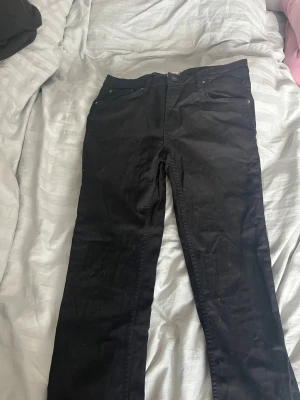 Svarta slim jeans från 157 - Svarta slim fit jeans från 157 med klassisk femficksdesign och dragkedjegylf. Snygg passform som sitter tajt längs benen och passar perfekt till en avslappnad eller trendig stil. Materialet är mjukt och stretchigt för extra komfort. Se måttet på bilderna 