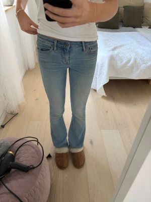 Ljusblå bootcut jeans - Säljer ett par ljusblå bootcut jeans med klassisk femficksmodell och låg midja. Jeansen har en lätt tvättad look och raka ben som går ut lite nedtill. Perfekta till sneakers eller boots för en avslappnad stil. Har dock två hål baktill! Vet inte storlek på de men de är stretchiga så funkar bra till S💕